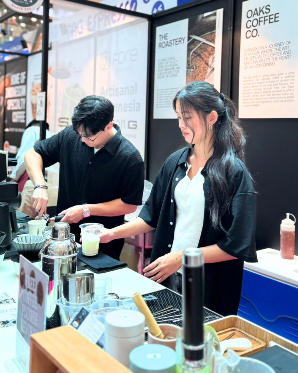 A barista expertly pouring latte art into a cup at Singapore Coffee Week